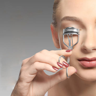 femme maquille yeux avec recourbe cils delta professionnel argent